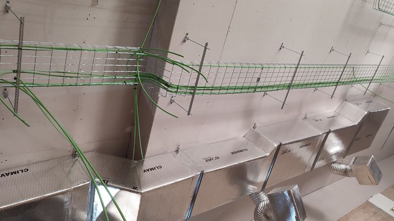 Red de conductos de fibra con rejillas de impulsión y bandeja de cableado en un local de Sevilla