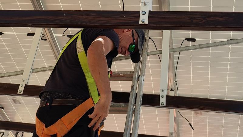 Instalador con arnés conectando los terminales MC4 del cableado de una instalación fotovoltaica