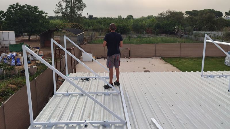 Soportes triangulares de aluminio atornillados a una cubierta de chapa para placas solares