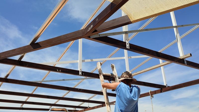 Instalador atornillando las correas de aluminio sobre las vigas de madera de una pérgola solar