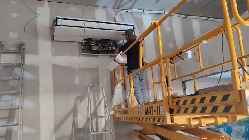 Técnico conectando la cortina de aire de un local comercial desde una plataforma elevadora