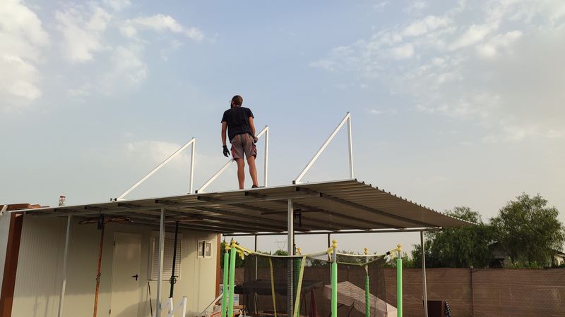 Instalador montando la estructura de placas solares sobre la cubierta metálica de un cobertizo